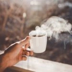 person holding white ceramic cup with hot coffee